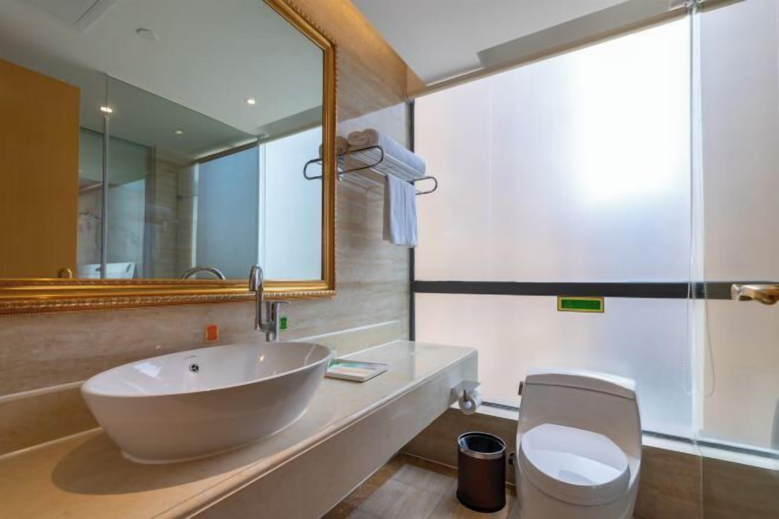 A modern bathroom with a large oval sink, a mirror, and a toilet.