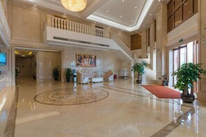 A spacious lobby with a polished marble floor, a central seating area with sofas, a staircase, and a large painting on the wall. - Vienna International Hotel (Yulin rongzhou bridge railway station shop ) (Rong County)