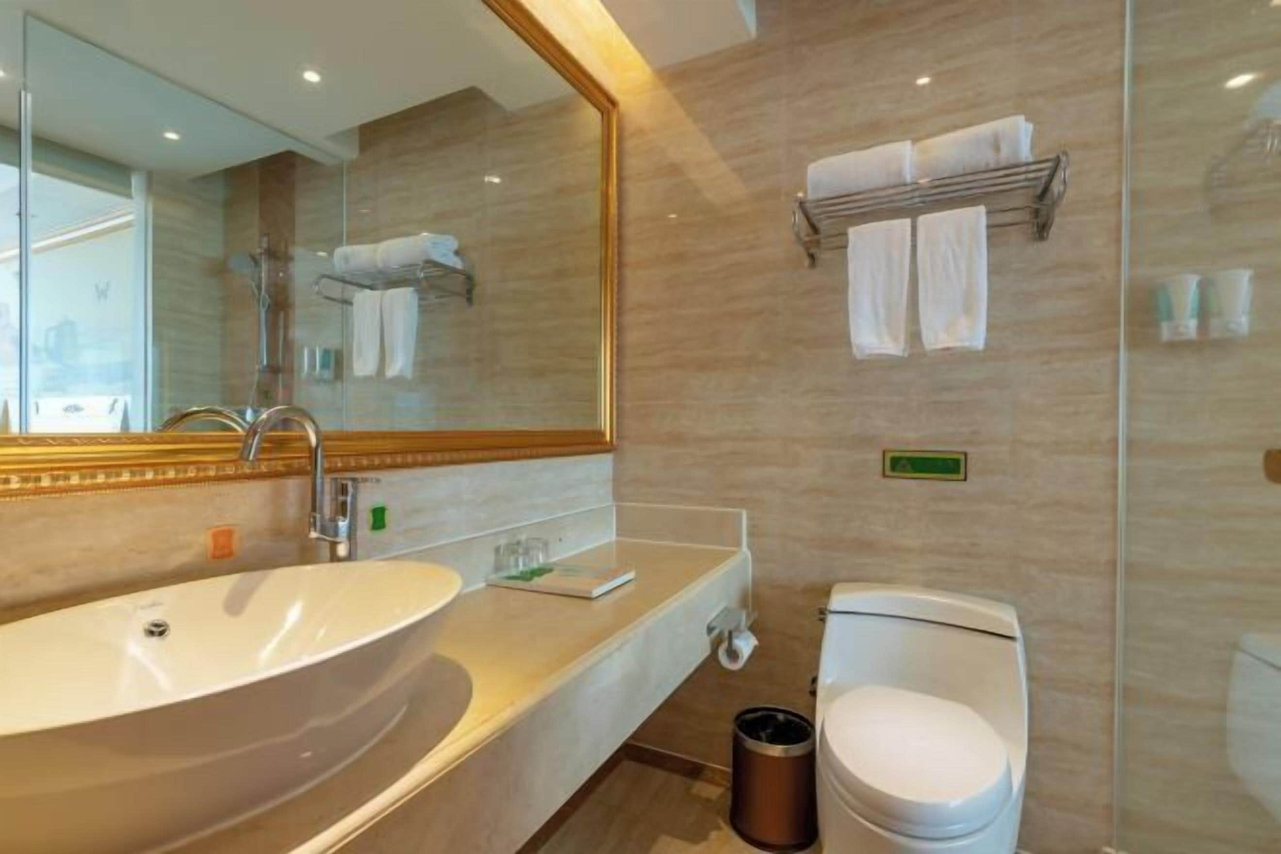 A modern bathroom with a large oval sink, a mirror, a towel rack, and a toilet.