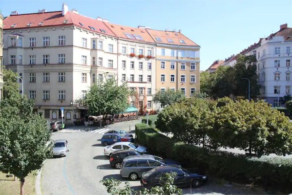 A multi-story building with a red-tiled roof, parked cars, and trees in a parking lot. - Cosy & Spacious Apartment, City Center, WiFi FREE (Hlavní mesto Praha)