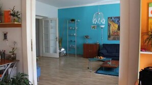A room with a blue wall, a wooden floor, a sofa, a coffee table, and a hanging light fixture. - Cosy & Spacious Apartment, City Center, WiFi FREE (Hlavní mesto Praha)