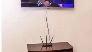 En tv-apparat som är monterad på en vägg, med ett trästativ placerat under den.