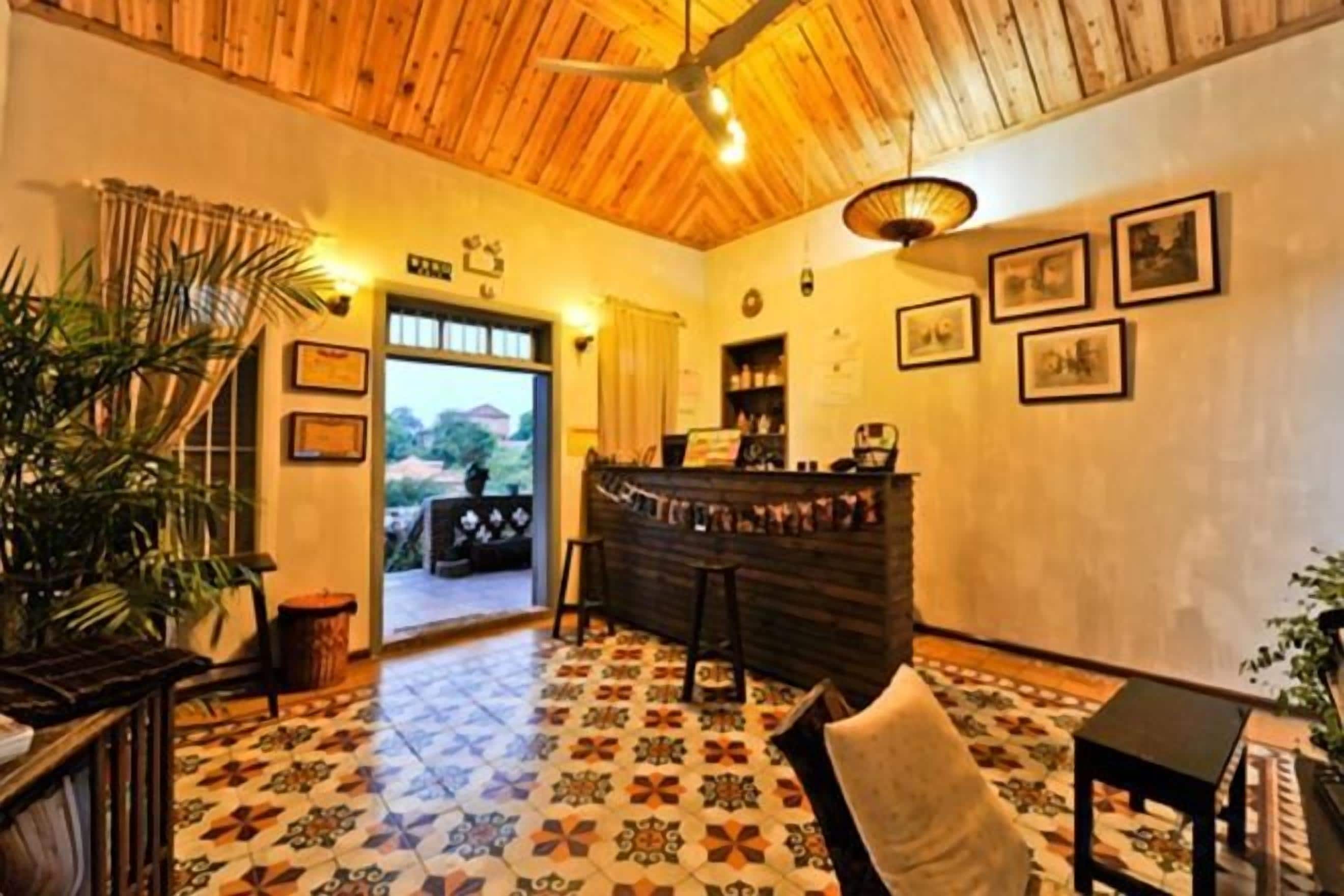 A hotel lobby with a wooden ceiling, a reception desk, and a patterned floor.