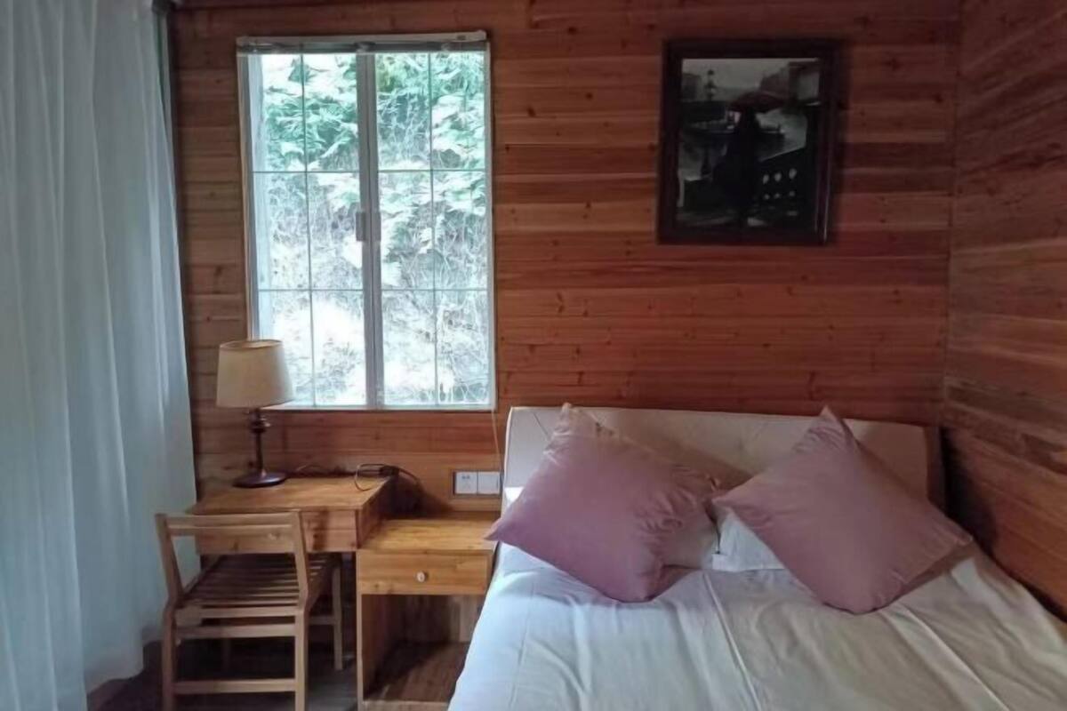 Una habitación de cabaña de madera con una cama, un escritorio y una ventana.