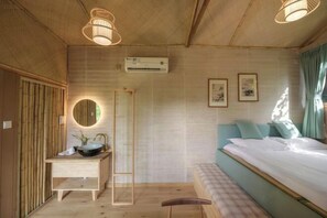 Une pièce avec un plafond en bois, un lit avec une tête de lit bleue, une table de chevet avec un miroir et un climatiseur fixé au mur.