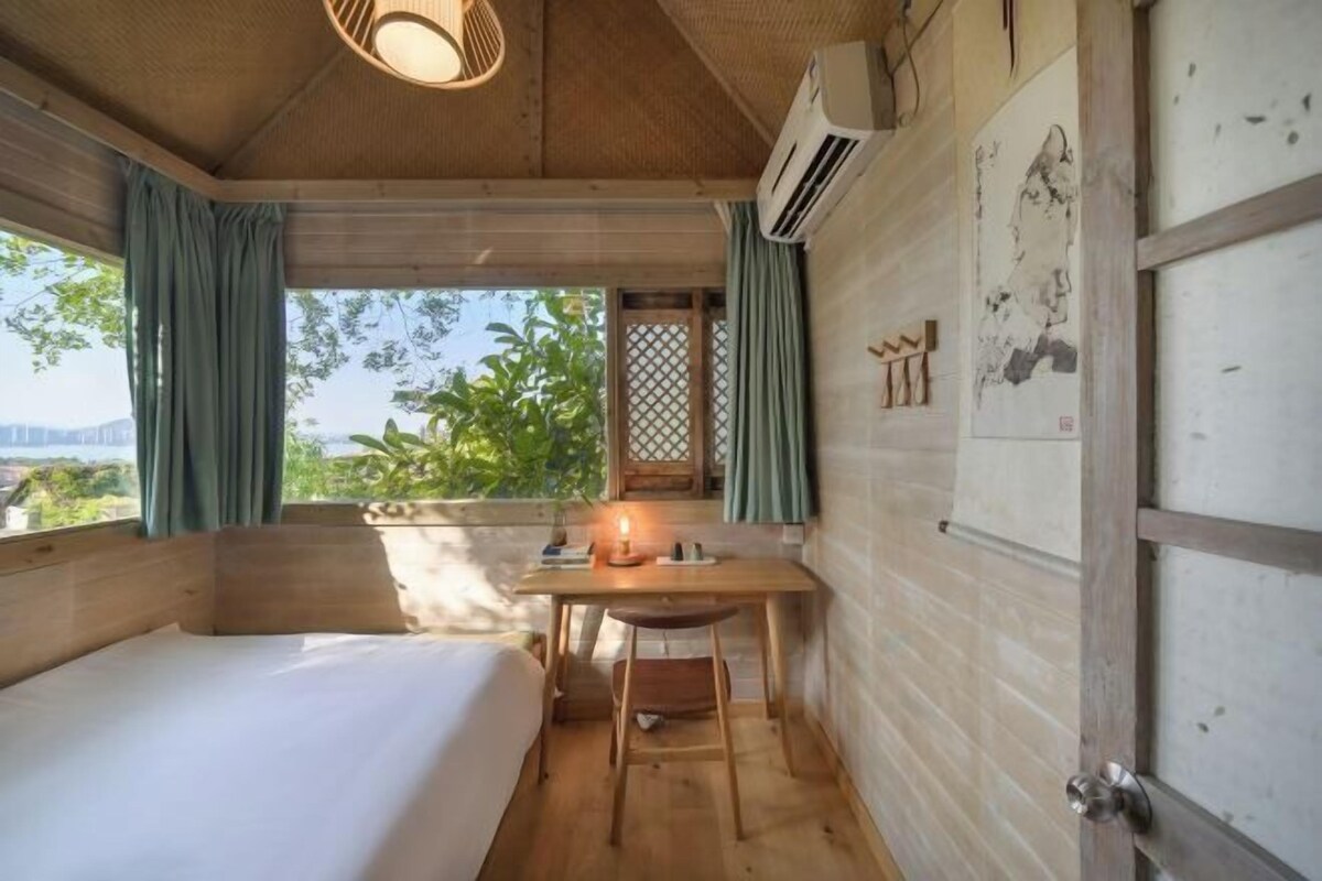 Une petite pièce comprenant un lit, un bureau et une fenêtre avec des rideaux.