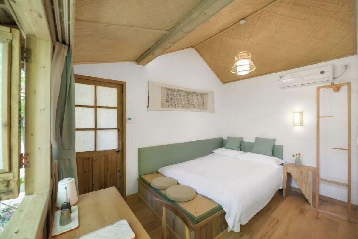 Une chambre confortable avec un lit en bois, une petite table et une fenêtre donnant sur un beau paysage.