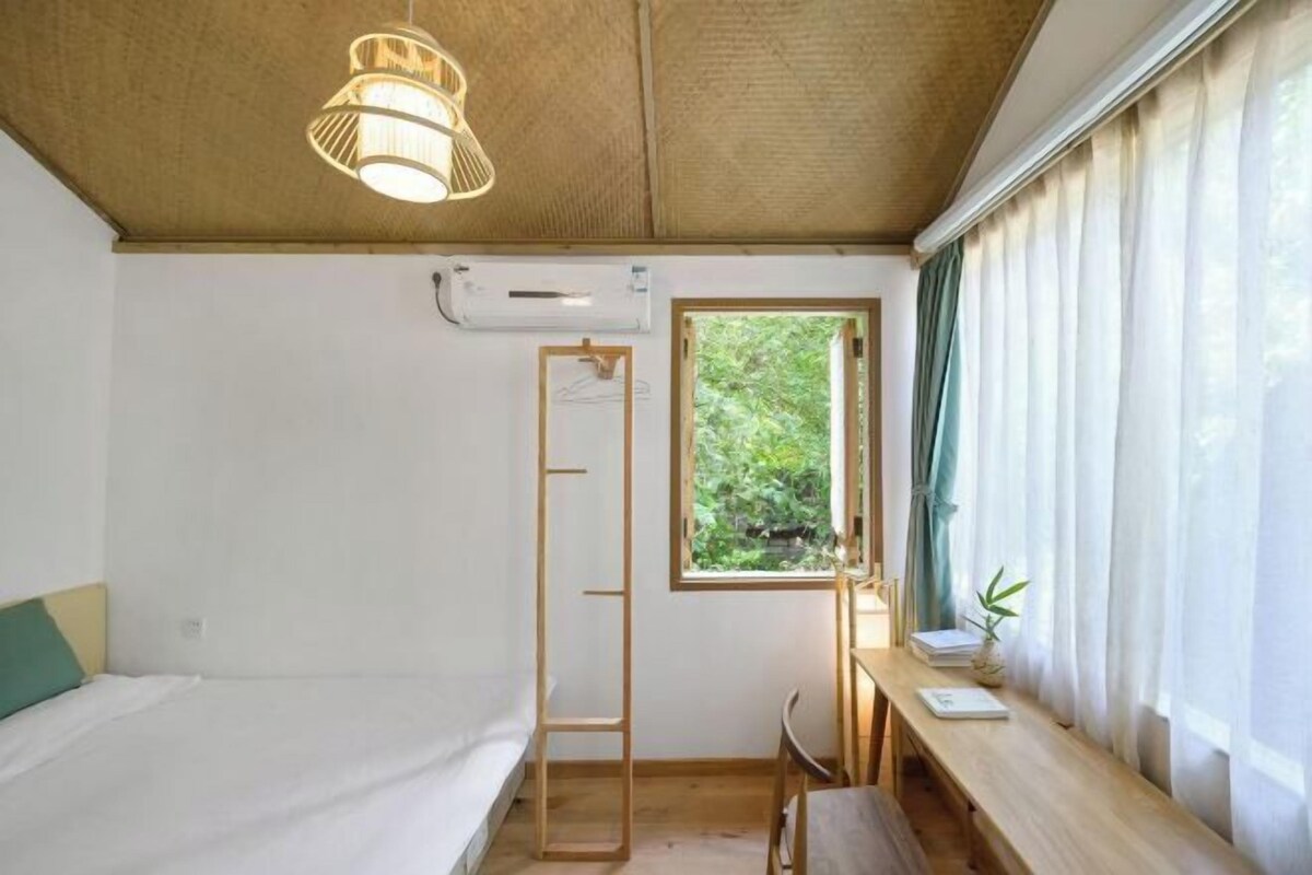 Une chambre avec un lit superposé, un bureau avec une chaise, une fenêtre avec des rideaux et un luminaire suspendu.