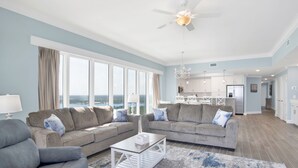 Ein geräumiges Wohnzimmer mit großem Fenster, Deckenventilator und Meerblick.