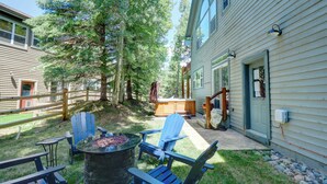 Takapiha, jossa on nuotiopaikka, Adirondack-tyyliset puutarhatuolit ja puinen terassi.