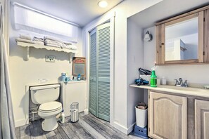 A bathroom with a toilet, a sink, a mirror, and a shower area. - Cozy Waterfront Cottage on Montsweag Bay! (Westport)