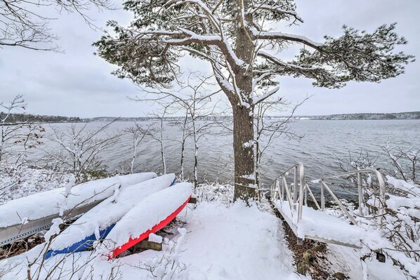A snow-covered lakeside with a tree and a metal railing. - Cozy Waterfront Cottage on Montsweag Bay! (Westport)