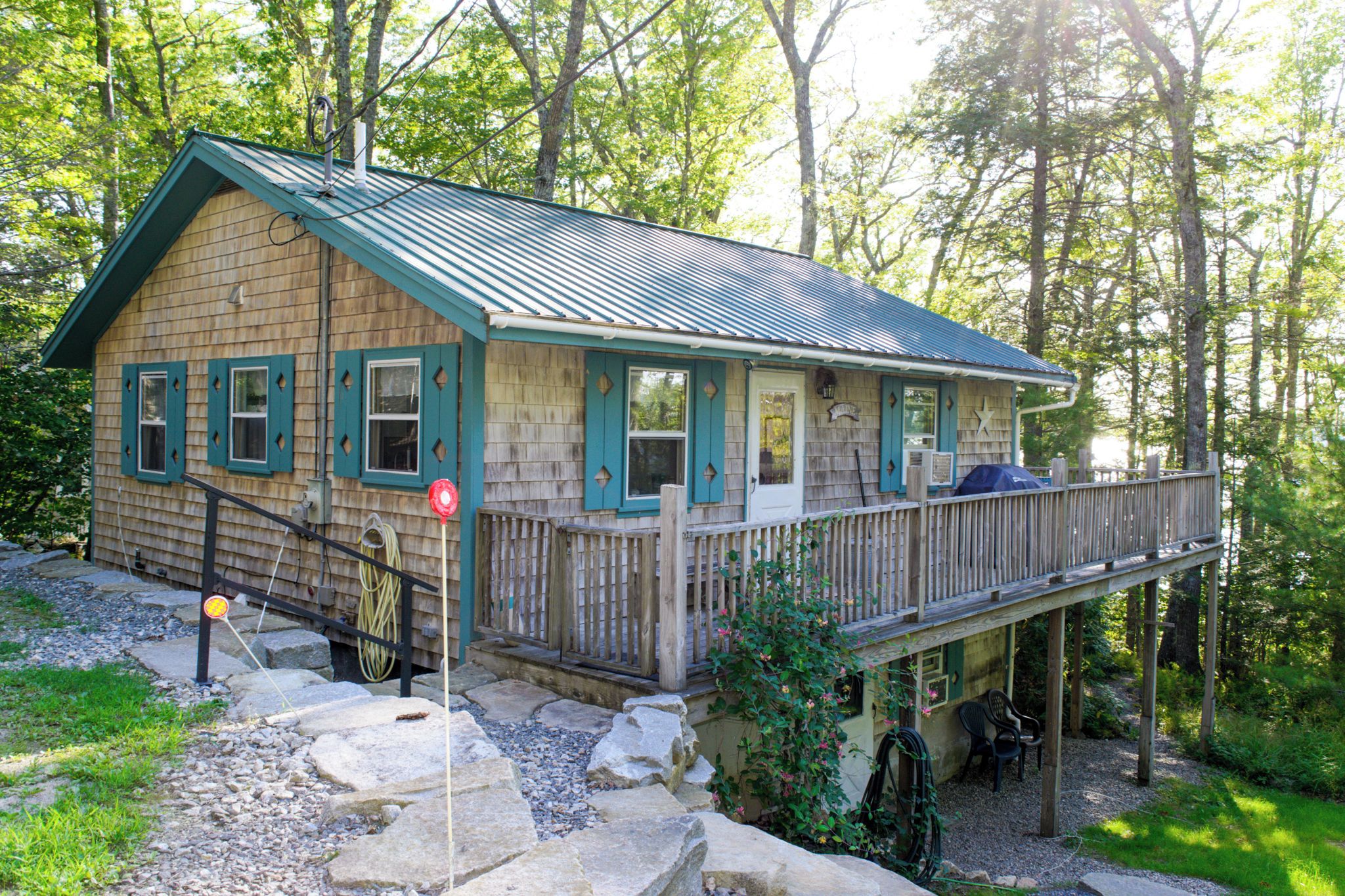 A cabin with a deck, surrounded by trees.