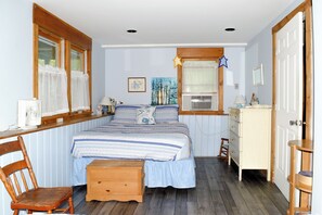 A bedroom with a bed, a wooden chair, a dresser, a window with curtains, and a painting on the wall. - Cozy Waterfront Cottage on Montsweag Bay! (Westport)