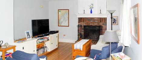 A living room with a television, a fireplace, and a bookshelf.
