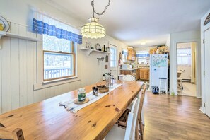 A kitchen with wooden cabinets, a long wooden table, and a hanging light fixture. - Cozy Waterfront Cottage on Montsweag Bay! (Westport)