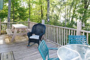 A wooden deck with a table, chairs, and a rocking chair. - Cozy Waterfront Cottage on Montsweag Bay! (Westport)