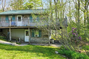 A two-story house with a balcony, a front door, and a small porch area. - Cozy Waterfront Cottage on Montsweag Bay! (Westport)