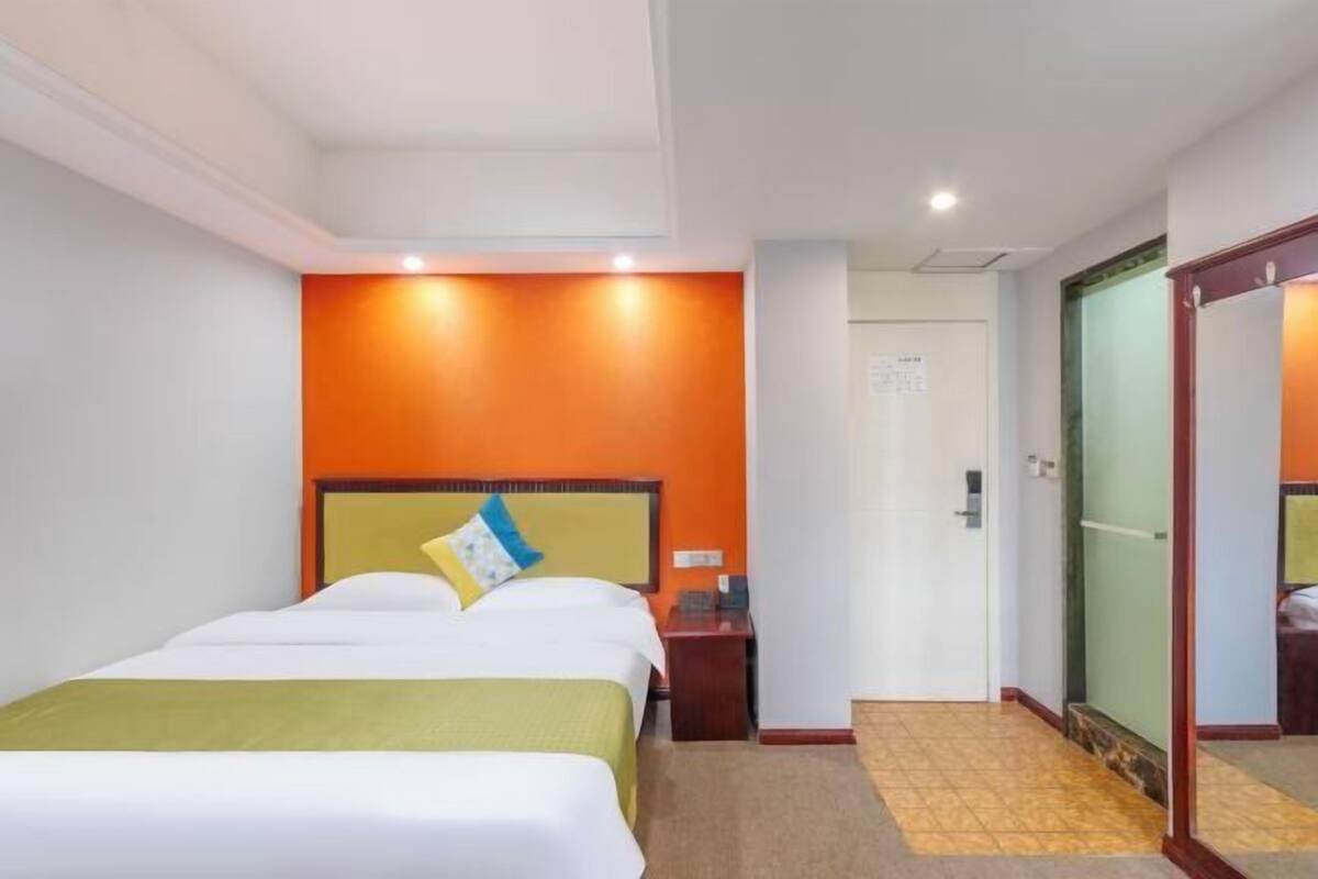 Una habitación de hotel con una cama grande, una mesita de noche y un espejo.
