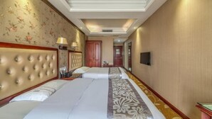 Una habitación de hotel con una cama grande, cabecero, mesita de noche, lámpara y televisor.