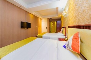 A hotel room with two beds, a television, and a patterned wallpaper.