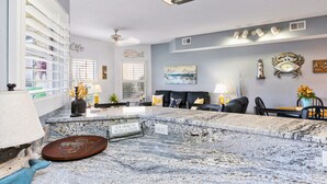 A living room with a marble countertop, a fireplace, a sofa, and a dining area. - Pool Just Steps Away | Easy Walk to Private Beach & Gulf Coast Fun (Destin)