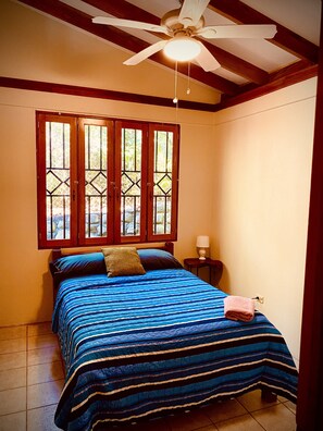 Cozy retreat with a large bed, wooden ceiling, and a window with a decorative pattern.