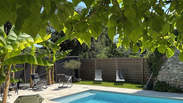 Un patio trasero con piscina, césped y valla de madera.