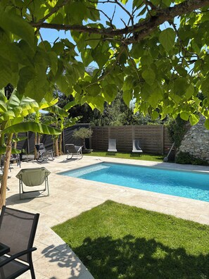 Un patio trasero con piscina, césped y valla de madera.