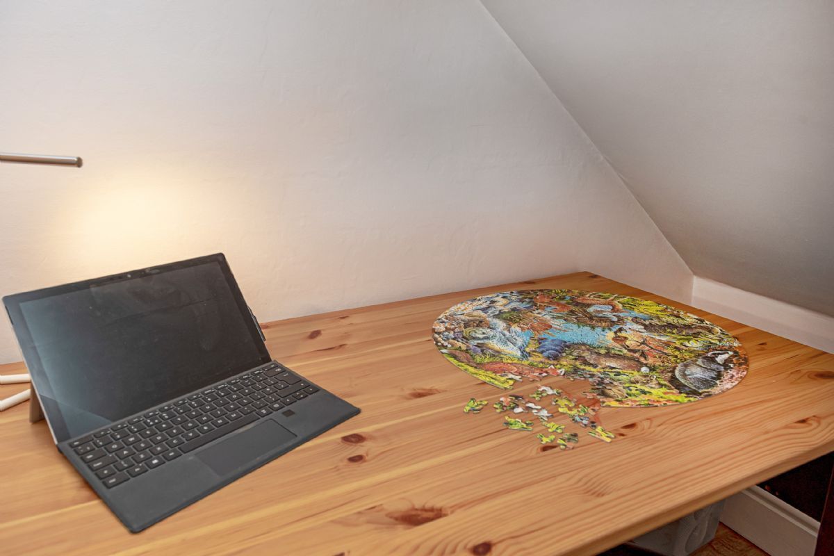Una computadora portátil sobre una mesa de madera con un rompecabezas incompleto.