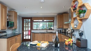 Una cocina moderna con armarios de madera, encimera de granito y un refrigerador para vino empotrado.