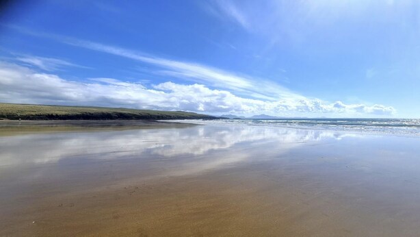 Una playa con cielo despejado y aguas tranquilas.