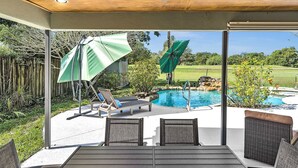Un espacio al aire libre techado con piscina, sillas de descanso y sombrillas.