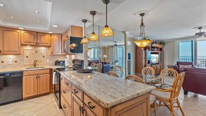 A spacious kitchen with wooden cabinets, a marble countertop, and pendant lighting. - Amazing views of the Gulf! Heated Pool, Private Beach (Siesta Key)