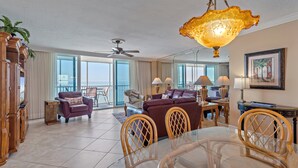 A spacious living room with a balcony, a dining area, and a ceiling fan. - Amazing views of the Gulf! Heated Pool, Private Beach (Siesta Key)