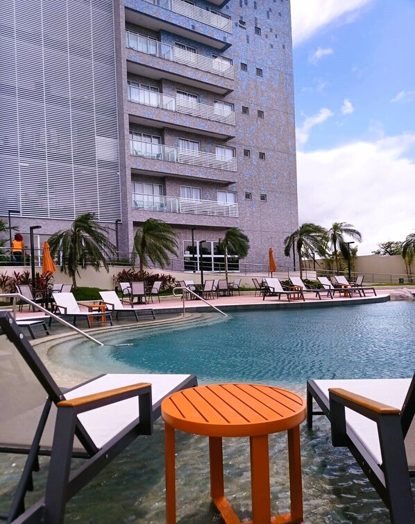 A hotel with a swimming pool, lounge chairs, and palm trees. - Aqualand Park & Resort Oficial (Salinópolis)