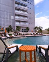 Um hotel com piscina, espreguiçadeiras e palmeiras.