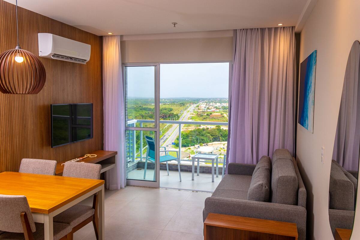 A modern living room with a balcony, a dining area, and a sofa.