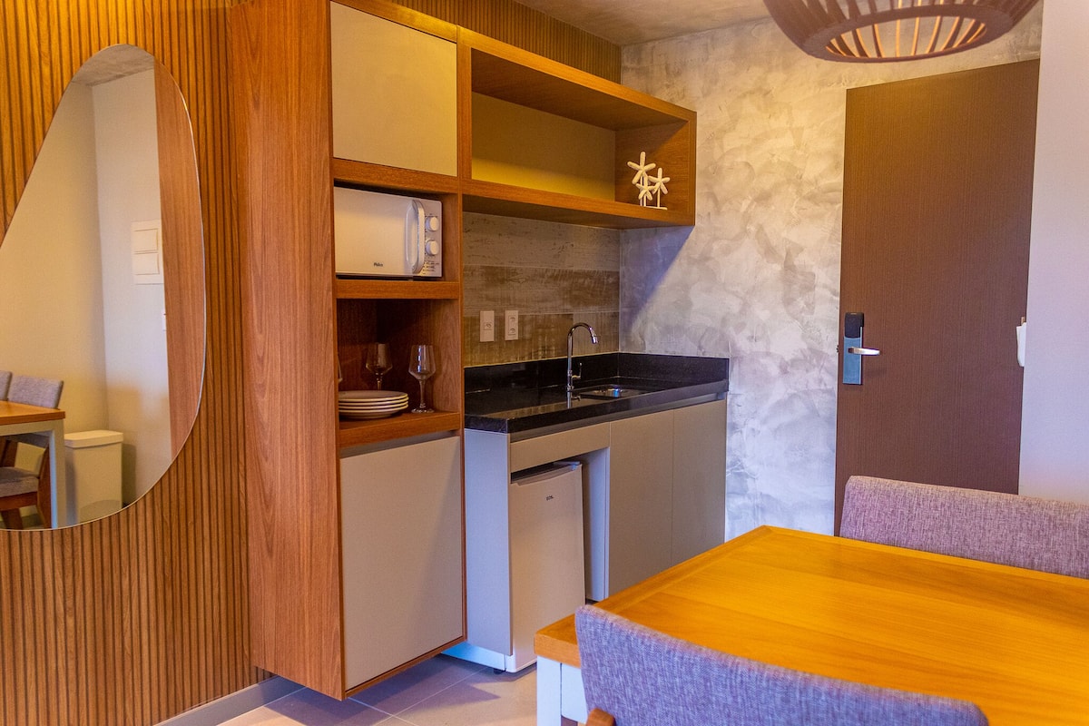A compact kitchen with wooden cabinetry, a built-in sink, and a small refrigerator.