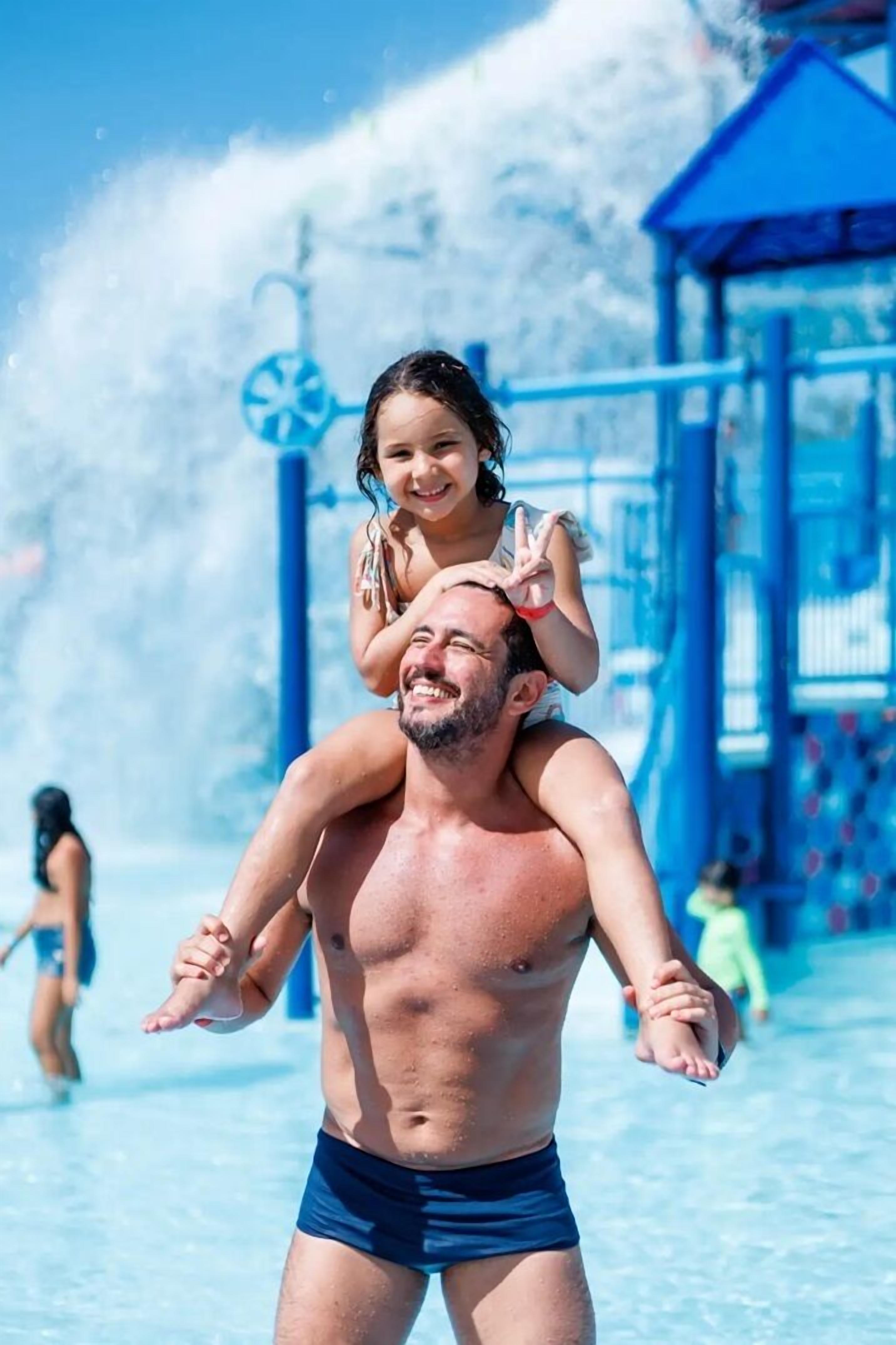 Um homem carregando uma criança nos ombros em um parque aquático.