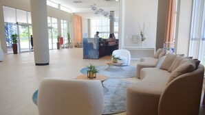 A spacious lobby with a reception desk, comfortable seating, and large windows. - Aqualand Park & Resort Oficial (Salinópolis)