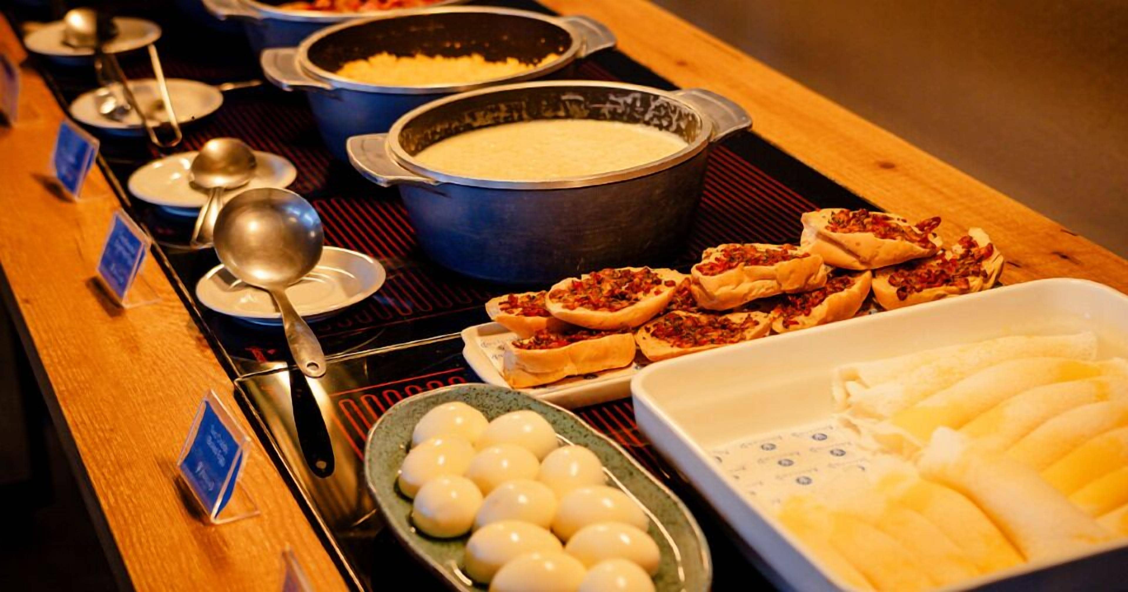 A buffet with various dishes, including a large pot of soup, a bowl of rice, and several small plates of food.