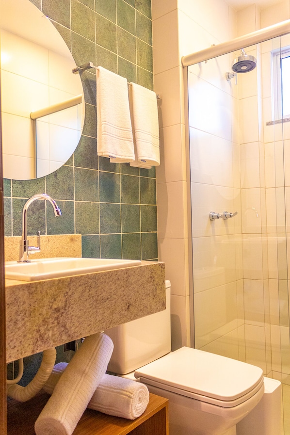 Un baño con lavamanos, espejo e inodoro.