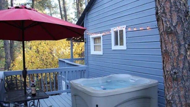 Een terras met een jacuzzi, een tafel met stoelen en een rode parasol.