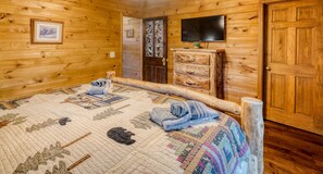A wooden cabin room with a bed, a dresser, a television, and a door. - 2 acre secluded Retreat Private creek Spa Gameroom (Morganton)