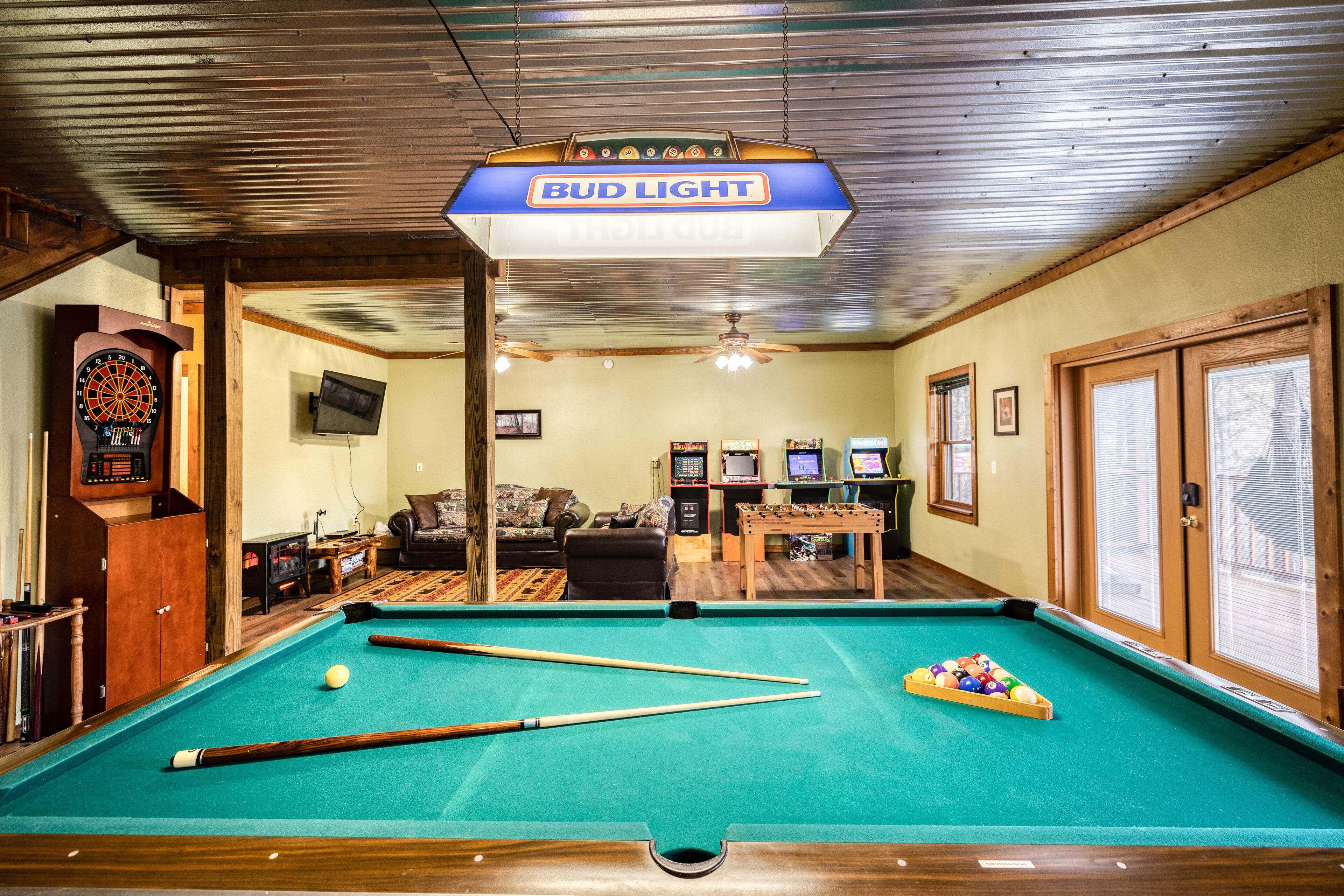 Een pooltafel met biljartballen, een dartbord en een aan de muur bevestigde televisie.