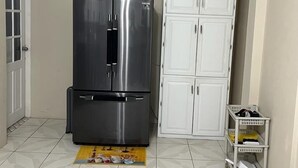 A compact kitchen with a stainless steel refrigerator, white cabinets, and a tiled floor. - Spacious One Bedroom Apartment in Palmiste (San Fernando)