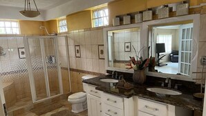 A bathroom with a walk-in shower, two sinks, and a large mirror. - Spacious One Bedroom Apartment in Palmiste (San Fernando)