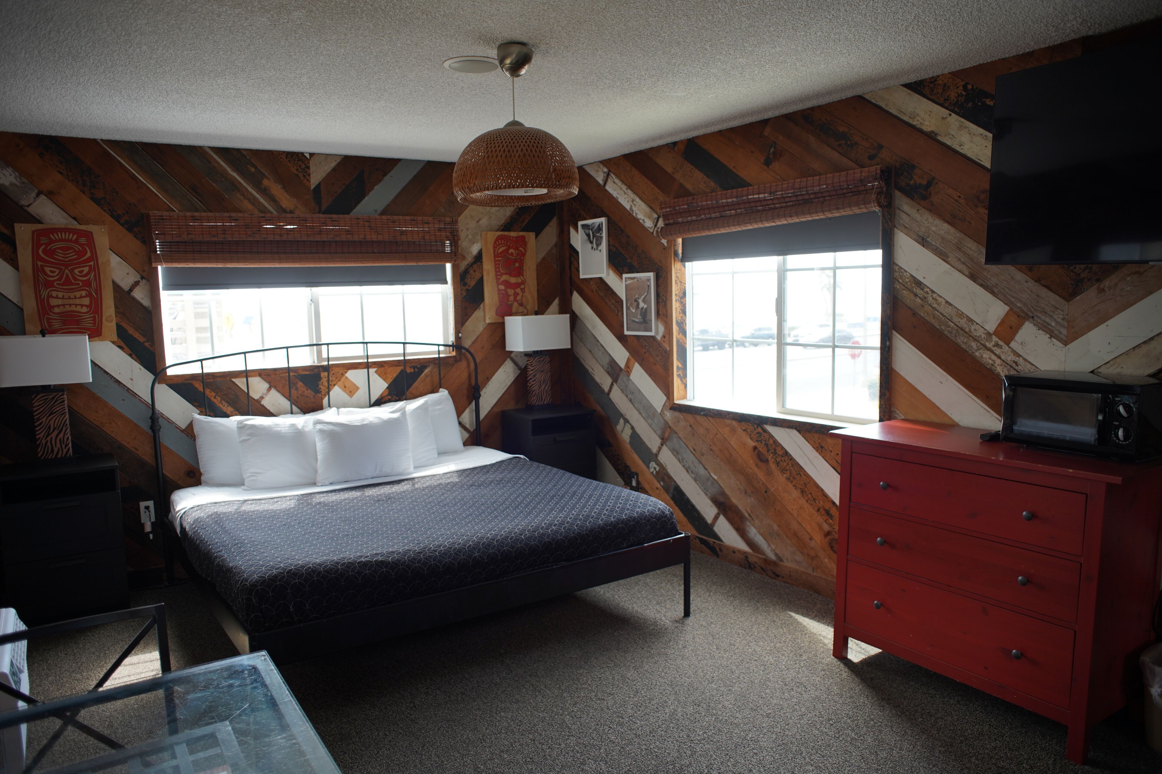 Un dormitorio con cama, cómoda, televisor y ventana con vistas.