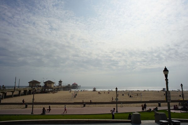 A beach with a pier, a walking path, and a view of the ocean.